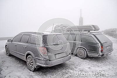 Completely frozen and snow-covered passenger car in a parking lot in winter in a thick fog Editorial Stock Photo