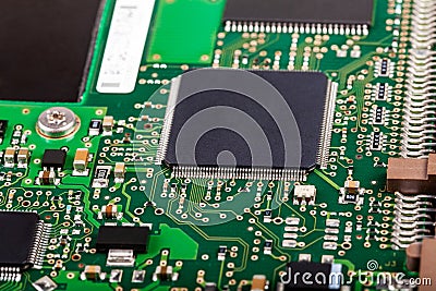 Complex electronics, green circuit board with a microcontroller, microprocessor control chip in the middle, extreme closeup detail Stock Photo