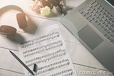 Compose music and education - paper sheet with musical notes, laptop and headphones on the artist desk Stock Photo