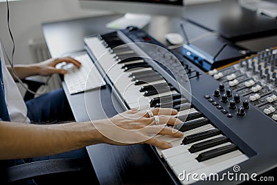 Composer hands on piano keys in recording studio. music production technology, man is working on pianino and computer Stock Photo
