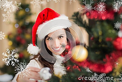Composite image of beauty brunette decorating a christmas tree Stock Photo