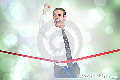 Composite image of businessman crossing the finish line while clenching fist Stock Photo