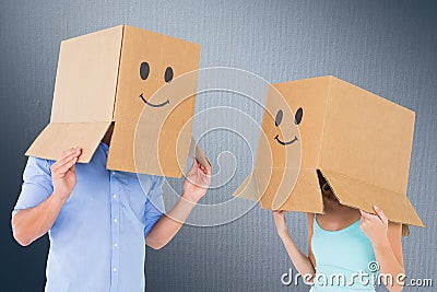 Composite image of couple wearing emoticon face boxes on their heads Stock Photo