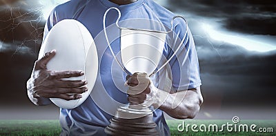 Composite image 3D of mid section of sportsman holding trophy and rugby ball Stock Photo
