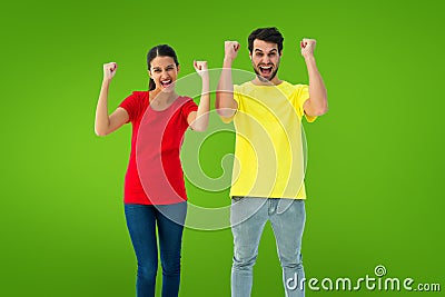 Composite image of excited couple cheering in red and yellow tshirts Stock Photo