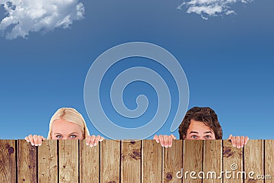 Composite image of happy couple hiding behind a whiteboard Stock Photo