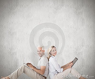 Composite image of happy couple sitting using laptop and tablet pc Stock Photo