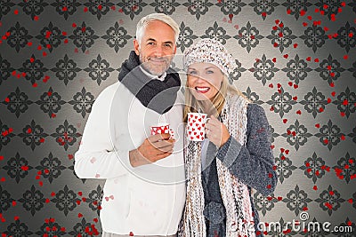 Composite image of happy couple in winter fashion holding mugs Stock Photo