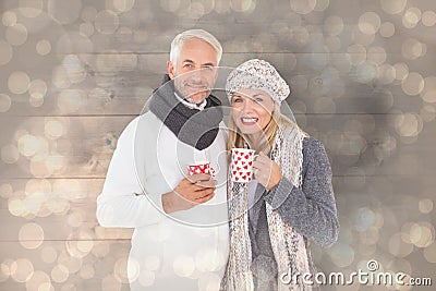 Composite image of happy couple in winter fashion holding mugs Stock Photo