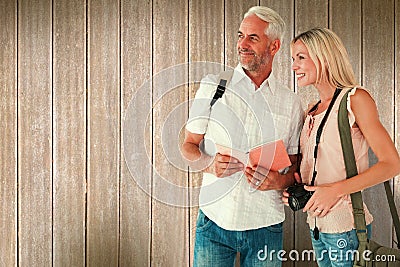 Composite image of happy tourist couple using the guidebook Stock Photo