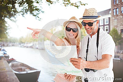 Composite image of happy tourist couple using map and pointing Stock Photo