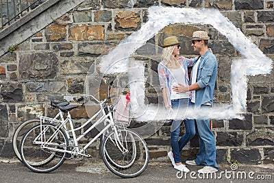 Composite image of hip young couple hugging by brick wall with their bikes Stock Photo