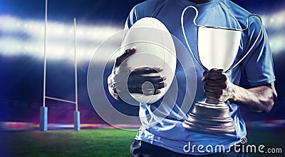 Composite image of mid section of sportsman holding trophy and rugby ball Stock Photo