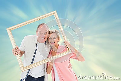 Composite image of older couple smiling at camera through picture frame Stock Photo