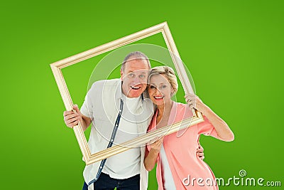 Composite image of older couple smiling at camera through picture frame Stock Photo