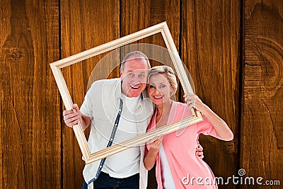 Composite image of older couple smiling at camera through picture frame Stock Photo