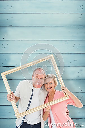 Composite image of older couple smiling at camera through picture frame Stock Photo