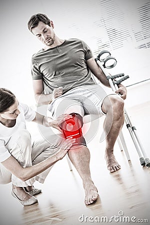 Composite image of physiotherapist checking man with crutches Stock Photo