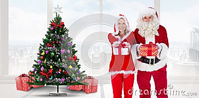 Composite image of santa and mrs claus smiling at camera offering gift Stock Photo