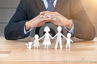 Composite image of underwriter protecting family in paper with his hands Stock Photo