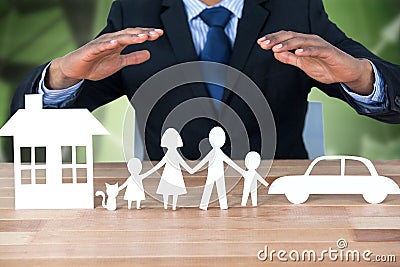 Composite image of underwriter protecting family in paper with his hands Stock Photo