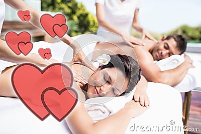 Composite image of a young couple receiving a back massage with love hearts Stock Photo