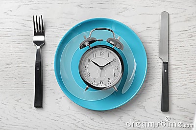 Composition with alarm clock, plate and utensils on light background Stock Photo