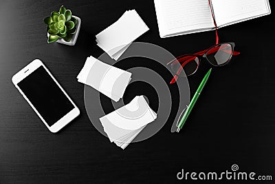Composition with blank business cards, mobile phone, eyeglasses and pen on dark table Stock Photo
