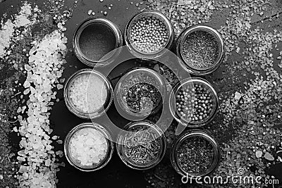 Composition of bottles with colored herbs and spices. Set of spices on dark grey background. Glass jars Stock Photo