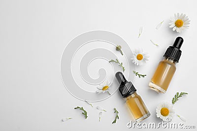 Composition with chamomile flowers and cosmetic bottles of essential oil on white background Stock Photo