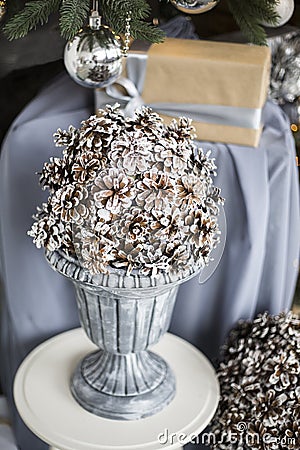 Composition from cones in a big silver vase of century. Against the background of a green fir-tree with silvery spheres and a gift Stock Photo