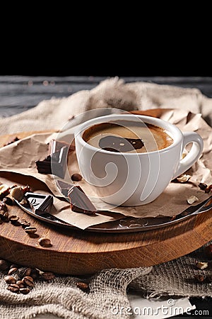 Composition with cup of coffee and served with coffee beans and chocolate on wooden chopping board Stock Photo