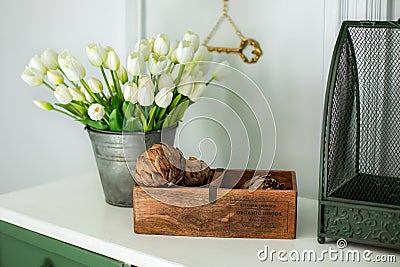 Composition of dried artichoke flowers in wooden box and a bouquet of white tulips in a vase as home decoration. Modern style flow Stock Photo