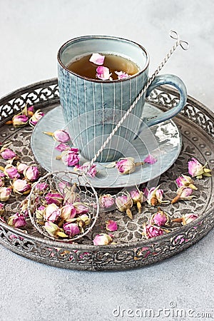 Composition with dried rose buds of tea and vintage sieve on tray Stock Photo