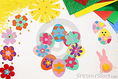 Composition of Easter eggs, wreath, flowers, sun, chicken, rabbit from multi-colored paper, step by step. Child makes crafts his Stock Photo