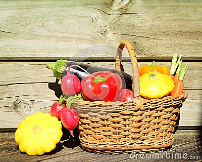 Composition with fresh vegetables arranged in a wicker basket on a wooden table Stock Photo