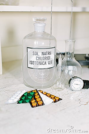 Glass bottle with latin label of isotonic solution, blister packs of different tablets, scales, glass flask and Stock Photo