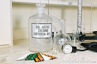 Glass bottle with latin label of isotonic solution, blister packs of different tablets, scales, glass flask and Stock Photo