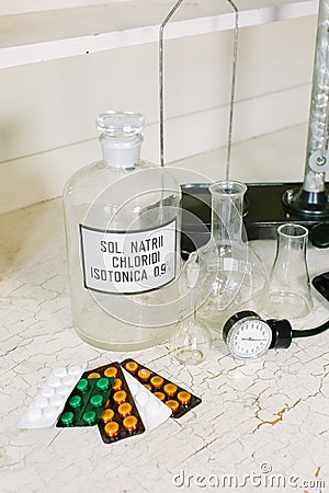 Glass bottle with latin label of isotonic solution, blister packs of different tablets, scales, glass flask and Stock Photo