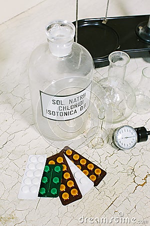 Glass bottle with latin label of isotonic solution, blister packs of different tablets, scales, glass flask and Stock Photo