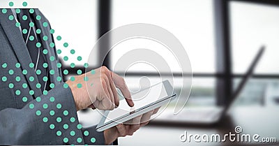 Composition of green dots and midsection of businessman using tablet over modern interiors Stock Photo