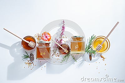 Composition of honey jars with honey sticks ,flowers and bee pollen on white background Stock Photo