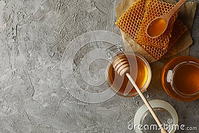 Composition with honeycombs honey and jars on gray background Stock Photo