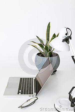 Composition with laptop on white tabletop with glasses, desklamp Stock Photo