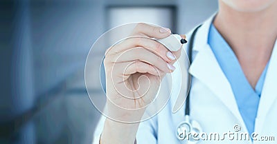 Composition of midsection of female doctor in lab coat with marker over out of focus hospital Stock Photo