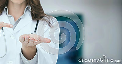 Composition of midsection of female doctor in lab coat pointing over out of focus hospital Stock Photo