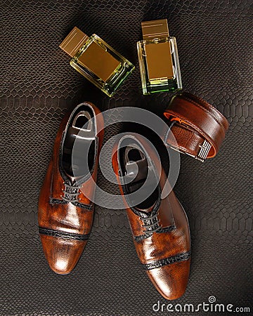 Composition of a pair of men`s shoes of brown color, two bottles of men`s perfume and men`s trouser belt against the background Stock Photo