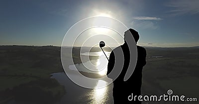 Composition of silhouette of golf player over landscape and blue sky with copy space Stock Photo