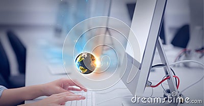 Composition of small glowing globe floating over midsection of woman using computer in office Stock Photo