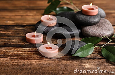Composition of spa stones, green leaves and burning candles Stock Photo
